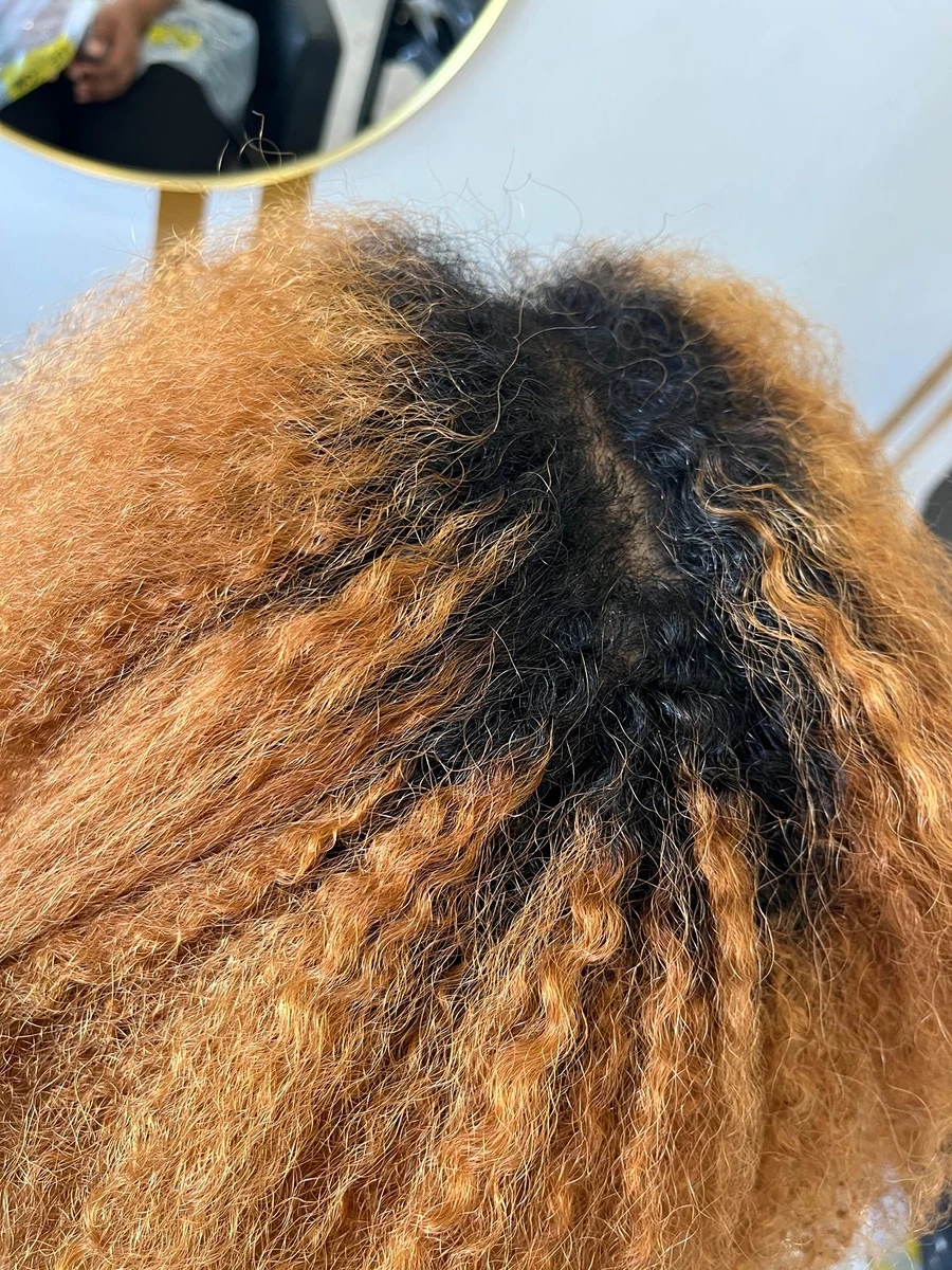 Raiz escura e cabelo encaracolado com pontas alaranjadas, antes do retoque